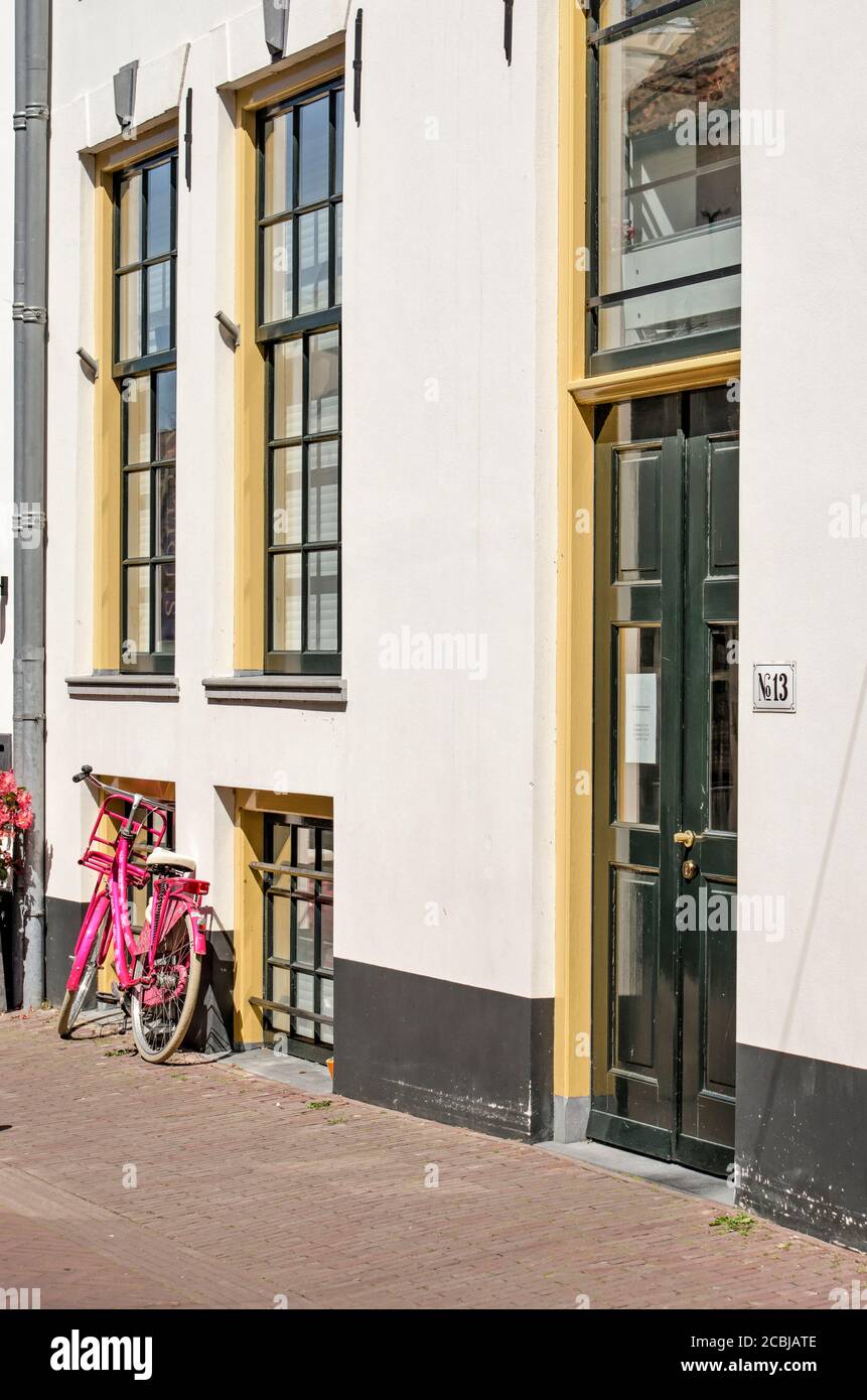 Hattem, pays-Bas, 31 juillet 2020 : façade de la vieille ville avec plâtre blanc et cadres de fenêtre verts et jaunes et vélo rose Banque D'Images