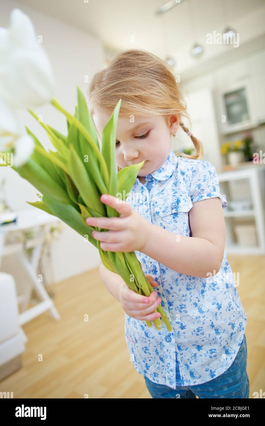La fille blonde porte un bouquet de tulipes blanches Banque D'Images