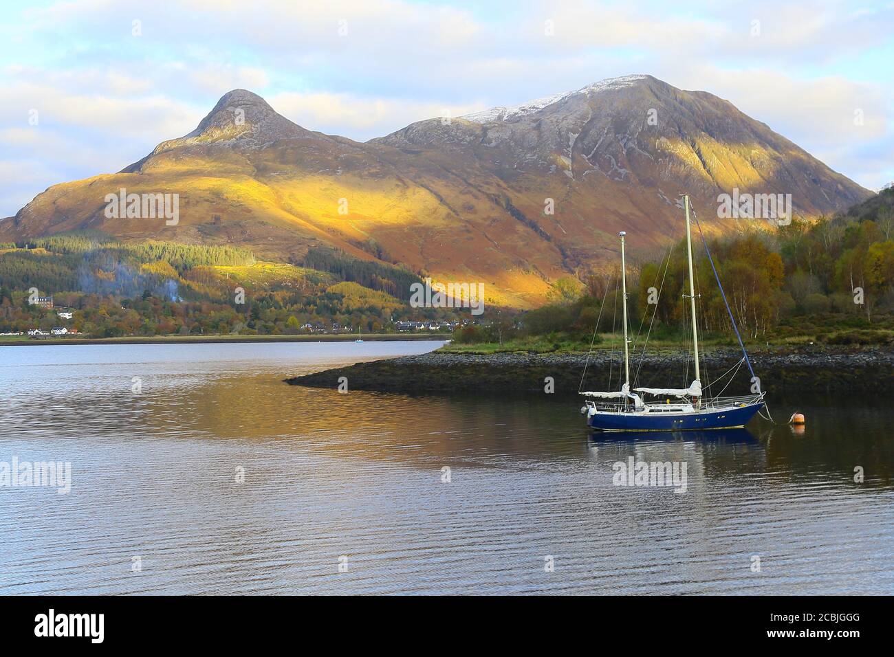 Montagnes écossaises avec un bateau bleu sur le loch. Banque D'Images