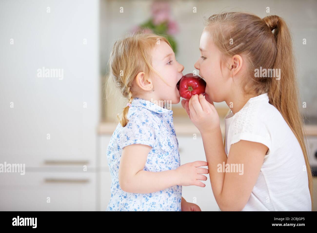 Deux enfants mangent une pomme rouge dans la cuisine Banque D'Images