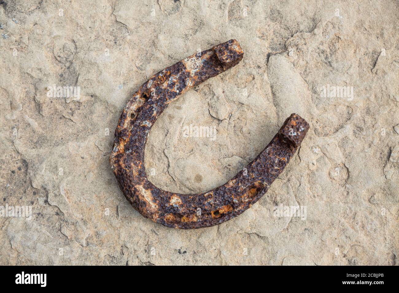 Un vieux fer à cheval rouillé a appuyé sur une grande pierre. Symbole du bonheur et de la chance. Banque D'Images
