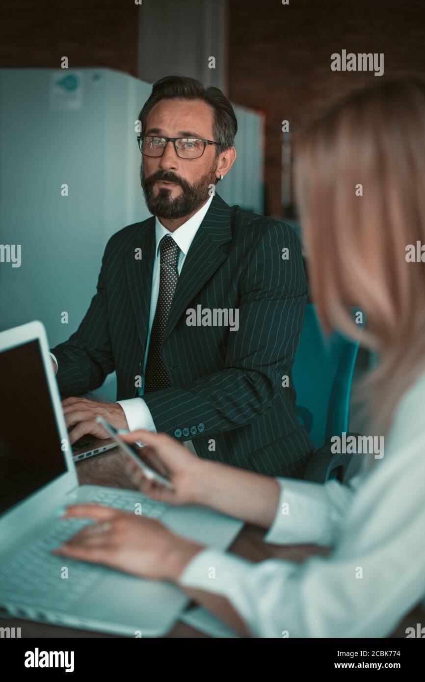 Homme d'affaires mature travaillant un ordinateur portable dans un bureau à espace ouvert ou dans un centre de travail. Banque D'Images