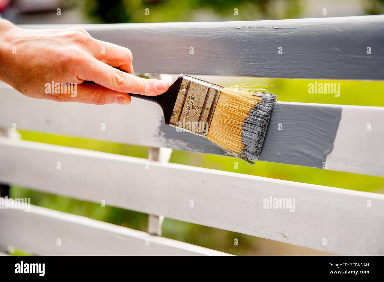 Peinture à la main de planches de bois blanches avec de la peinture grise à l'aide d'un pinceau. Banque D'Images