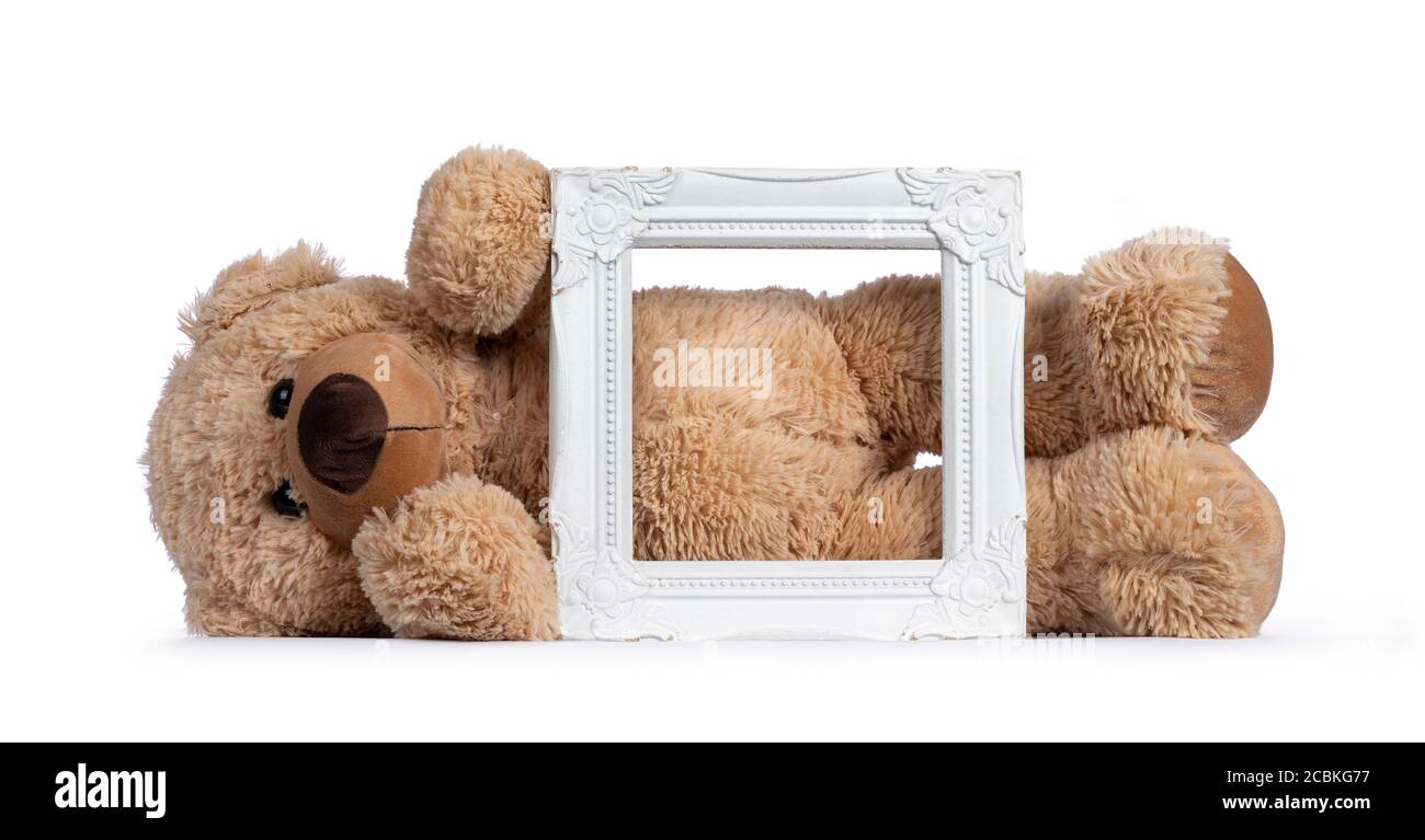 Mignon nouveau brun clair jouet ours en peluche derrière blanc cadre photo vide. Isolé sur fond blanc. Banque D'Images