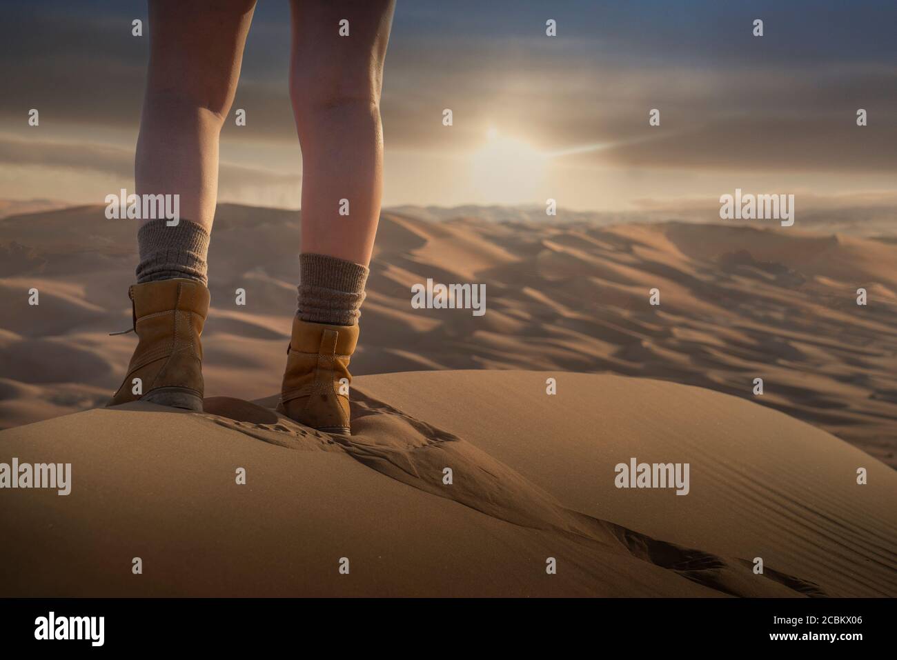 Les pieds de womans sur une dune de sable géante dans le désert au coucher du soleil, partie basse, Abu Dhabi, eau Banque D'Images