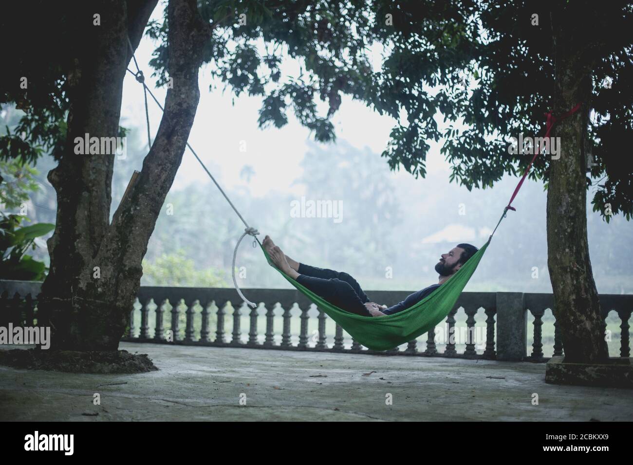 Homme relaxant dans un hamac, Vietnam Banque D'Images