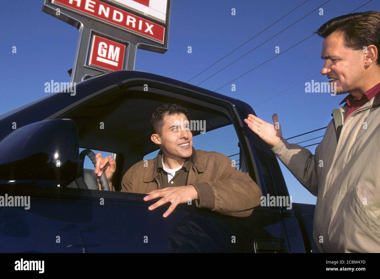 Austin, Texas USA, 2006: Un jeune homme hispanique est assis à l'intérieur d'un camion neuf qu'il pourrait acheter tandis que le vendeur pose le véhicule. ©Bob Daemmrich Banque D'Images