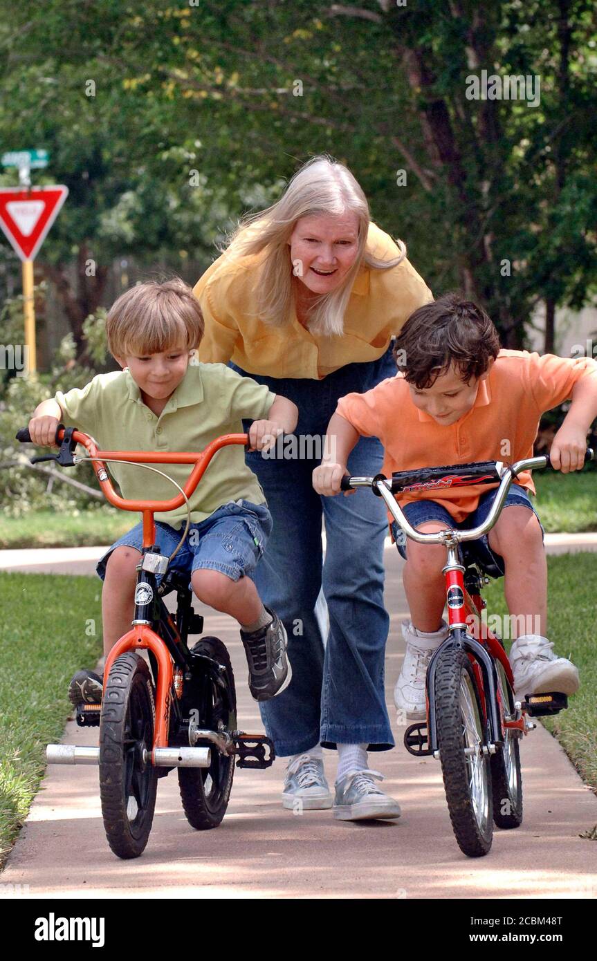 Killeen, Texas le 30 mai 2006 : Marilyn Nolen, 61 ans, qui avait des jumeaux au milieu de la cinquantaine grâce à un traitement de FIV utilisant des œufs donnés, observe ses enfants Travis (cheveux blond à gauche) et Ryan (cheveux foncés à droite) faire du vélo chez eux près de fort Hood, Texas. ©Bob Daemmrich Banque D'Images