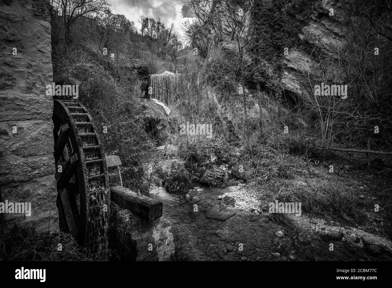 Effet noir et blanc de cascade dans une vallée avec un ancien moulin Banque D'Images