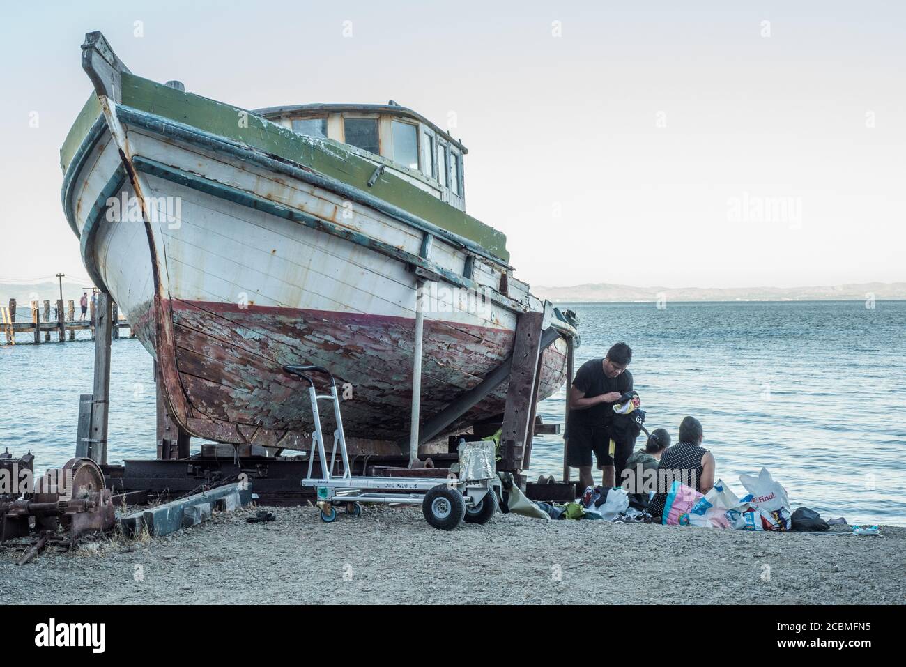Une famille peut pique-niquer à côté de Sea Breeze et d'un vieux bateau de pêche à la crevette qui se trouve sur la plage du parc national de China Camp en Californie. Banque D'Images