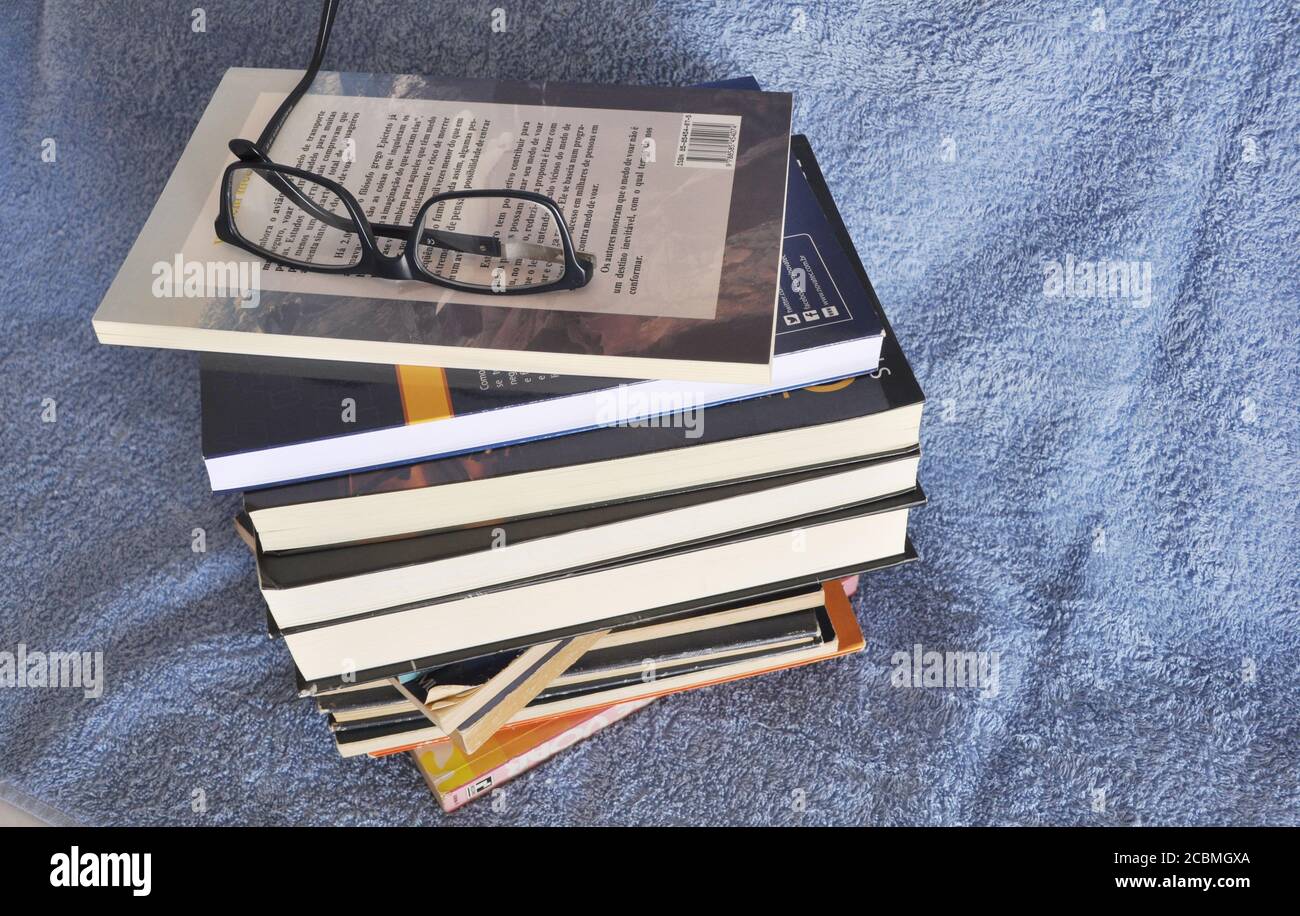 Pile de livres pour l'étude, divers sujets avec des lunettes de lecture sur fond bleu, Brésil, Amérique du Sud Banque D'Images