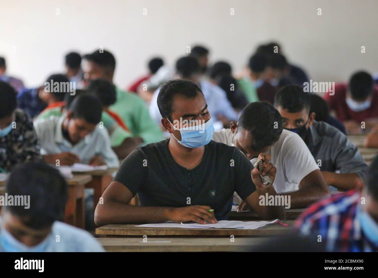 Les candidats portant un masque facial comme mesure préventive lors d'un test de recrutement pour un poste de pompier sous le service des incendies et la Défense civile dans un collège dans un contexte de crise du coronavirus (COVID-19) à Dhaka. Banque D'Images