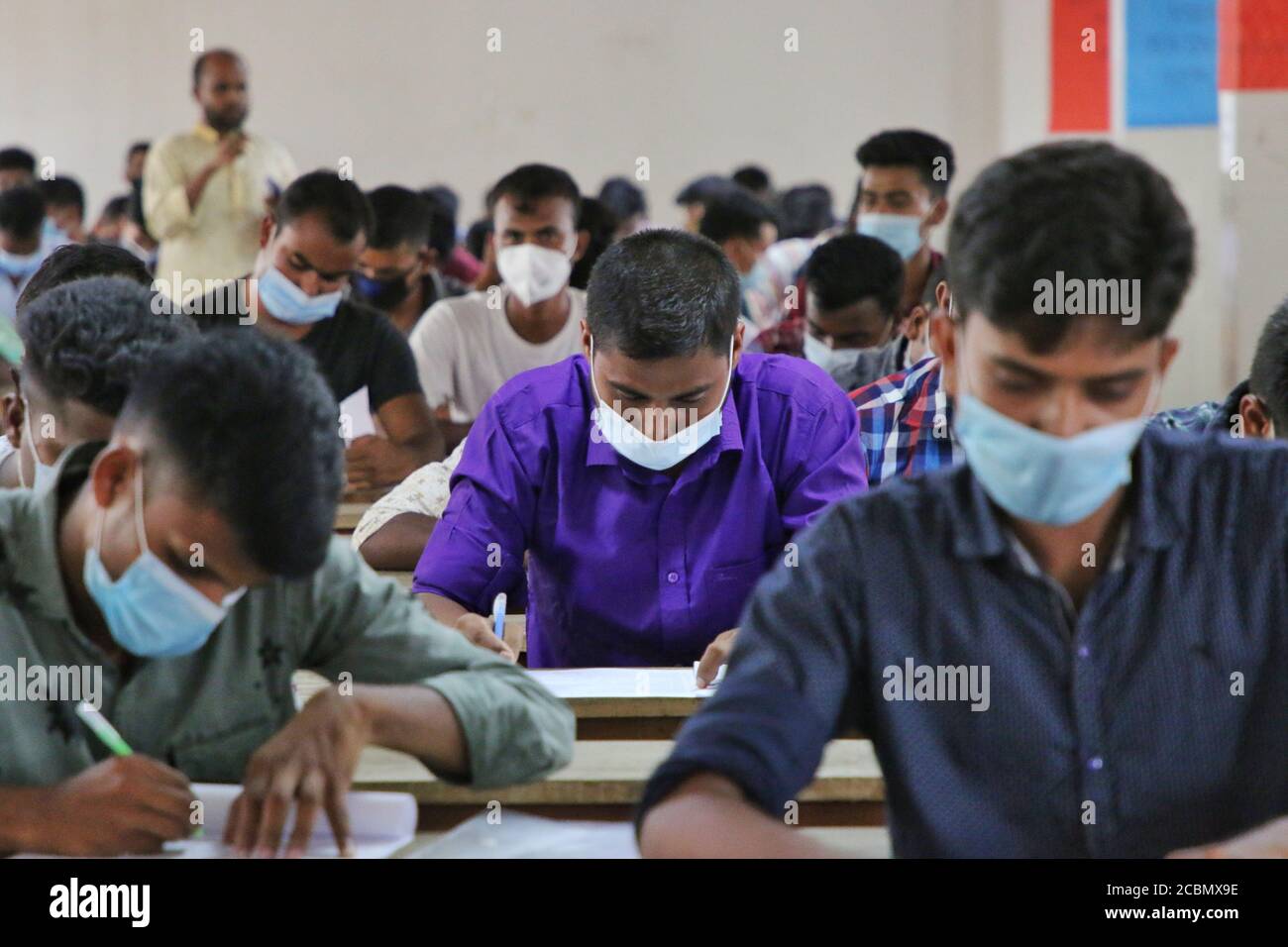Les candidats portant un masque facial comme mesure préventive lors d'un test de recrutement pour un poste de pompier sous le service des incendies et la Défense civile dans un collège dans un contexte de crise du coronavirus (COVID-19) à Dhaka. Banque D'Images