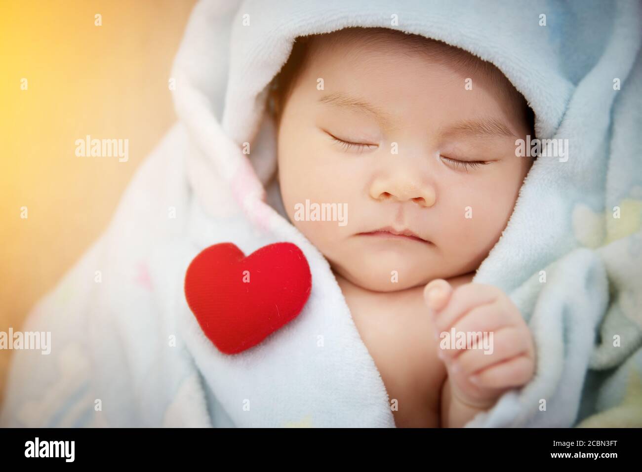 Famille amour concept de relation : coeur rouge mis sur le sommeil mignon bébé asiatique. Adorable nouveau-né asiatique modèle de femme dans sa première année Banque D'Images