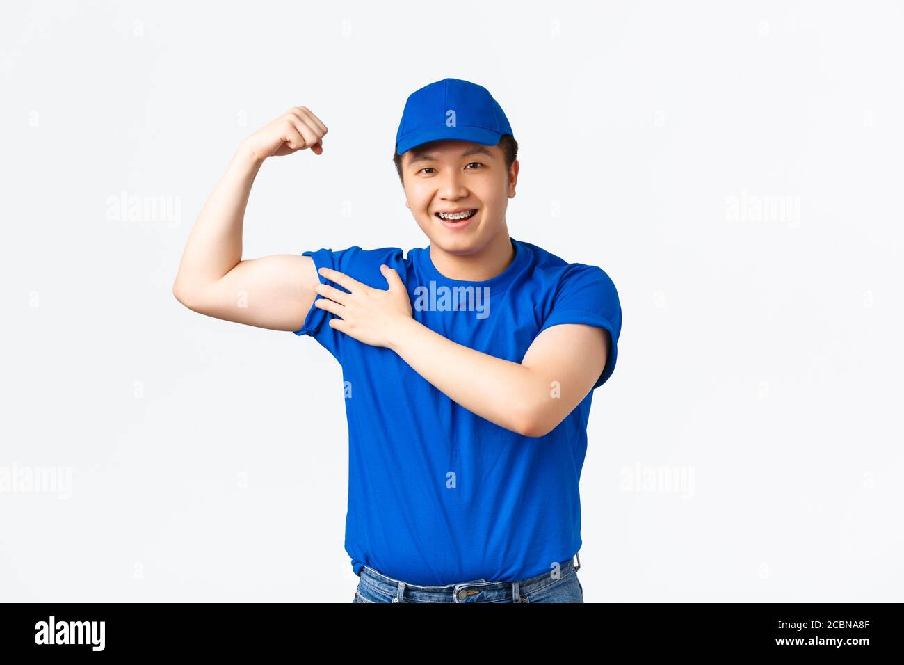 Portrait d'un homme de livraison asiatique souriant et amical montrant ses muscles, des biceps flexibles et regardant heureux, s'assurer que les colis des clients sont en sécurité, porter Banque D'Images