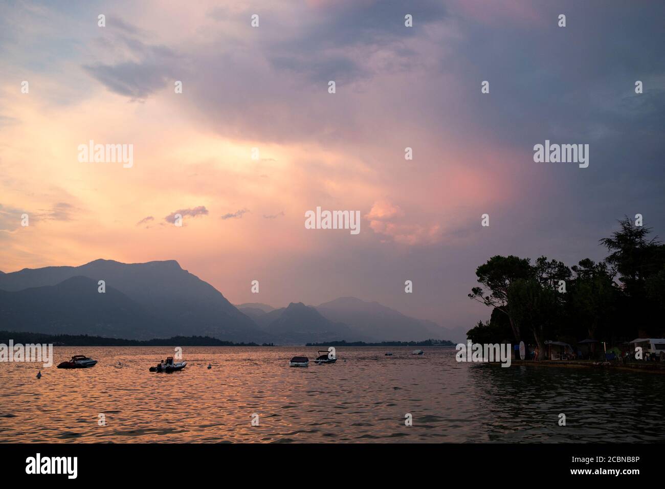 Magnifique coucher de soleil violet avec brume rose sur le lac de Garde avec des bateaux fixes. Manerba del Garda, Lombardie, Italie. Banque D'Images