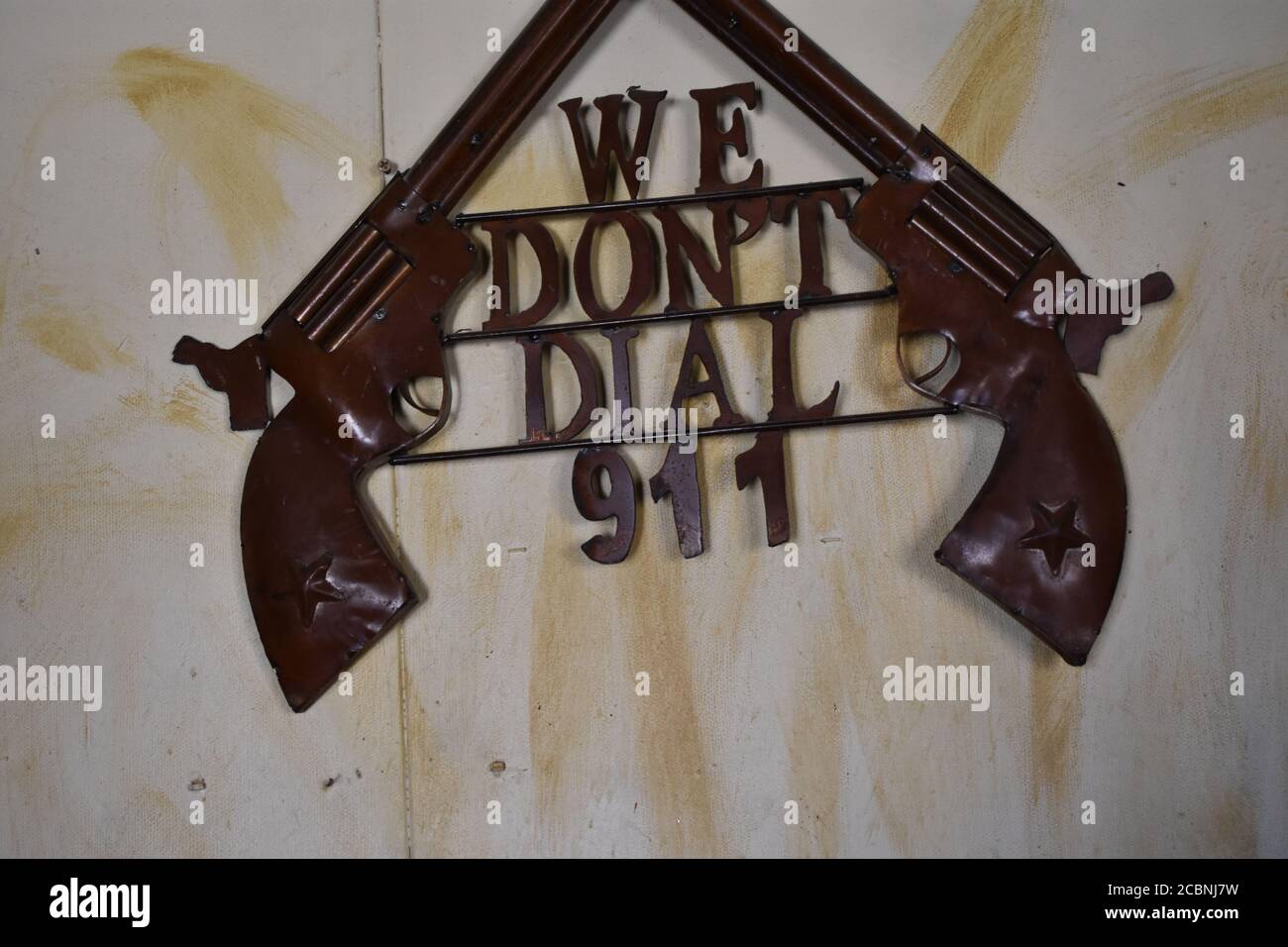 Gros plan de deux fusils de cow-boy et un texte 'nous ne sommes pas composez 911 pi sur un mur Banque D'Images