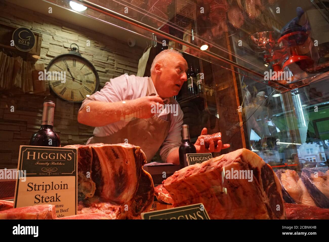 Comptoir de vente de viande de boucherie Higgins, un préposé qui montre de la viande aux clients Banque D'Images