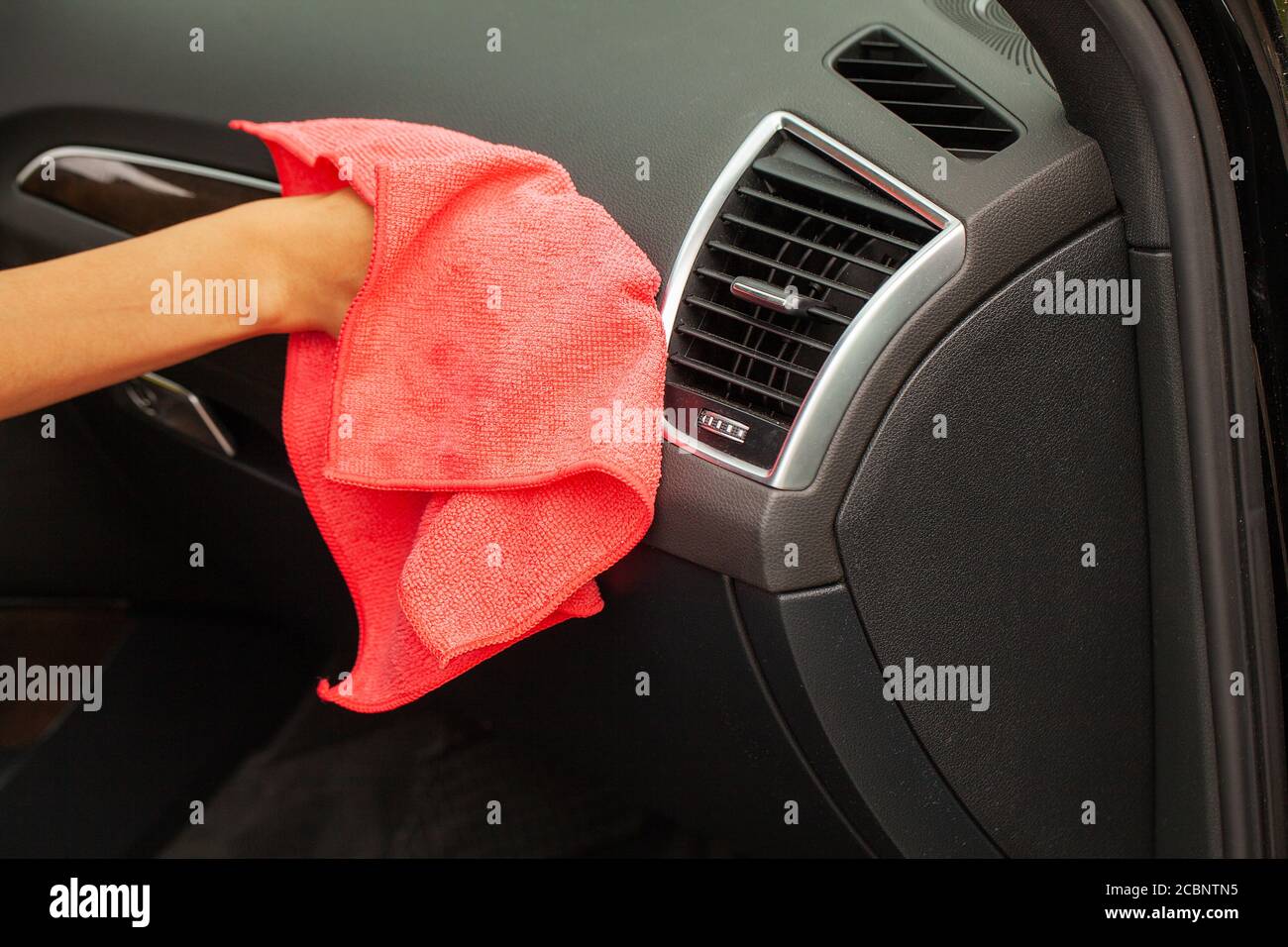 Gros plan d'une femme essuyant l'intérieur de la voiture avec un chiffon rouge Banque D'Images