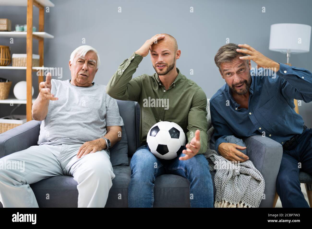 Des hommes contrariés regardant la défaite de l'équipe de football à la télévision Banque D'Images