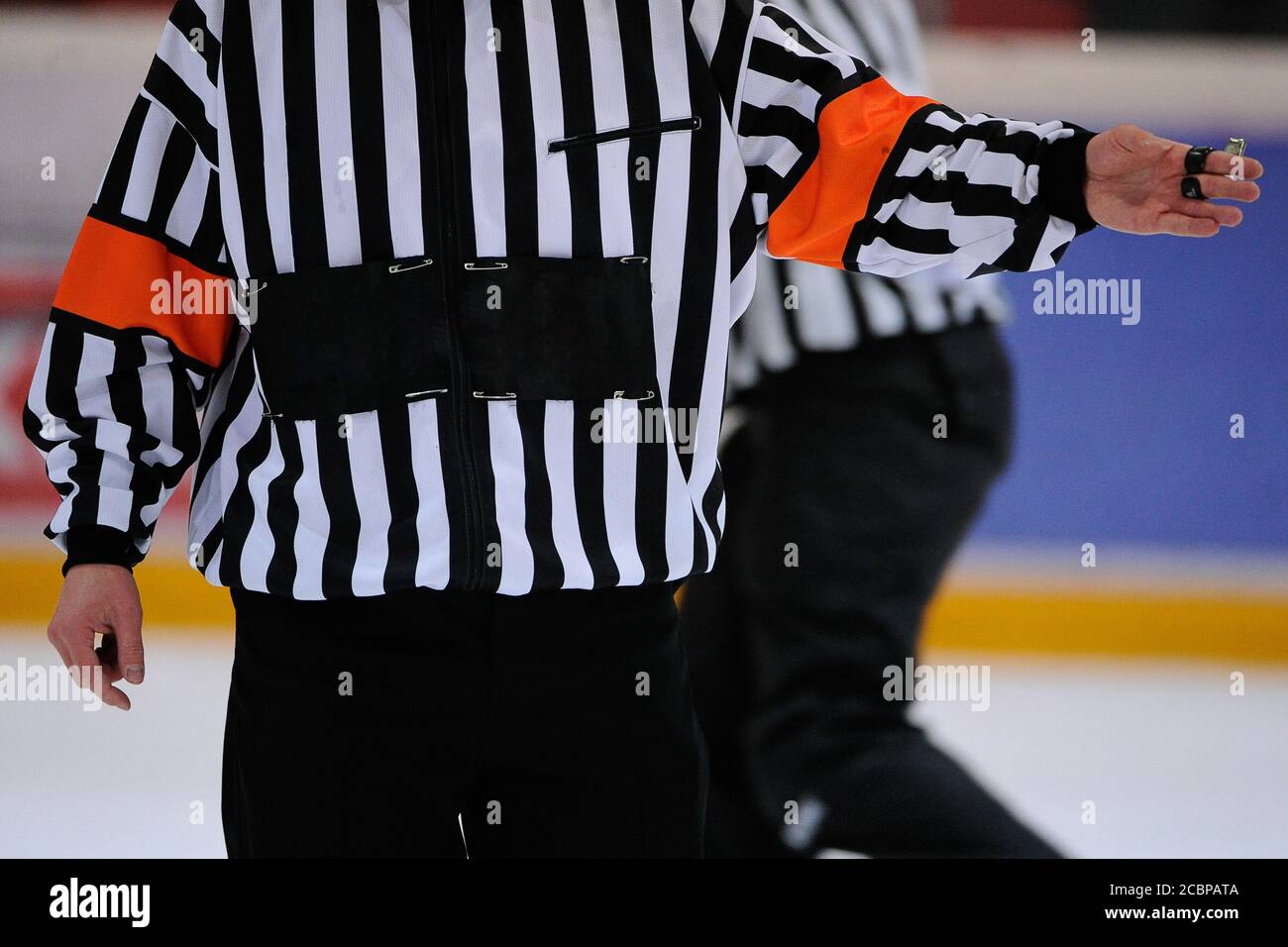 Gros plan d'un arbitre de hockey sur glace tenant un sifflet et donnant un signe aux joueurs. Banque D'Images