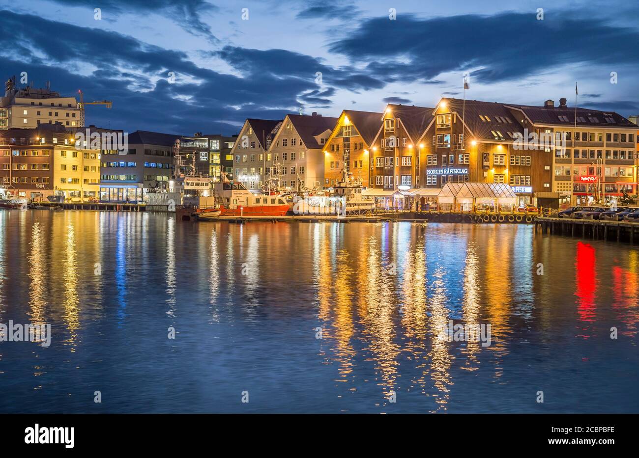 Rangée illuminée de maisons au port avec réflexion dans la mer, nuit polaire, Tromsoe, Troms, Norvège Banque D'Images