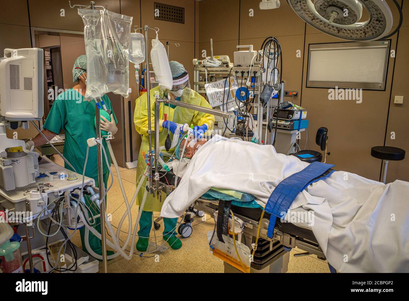 Un anesthésiste en équipement de protection ventilant un patient Covid-19 une salle d'opération Banque D'Images