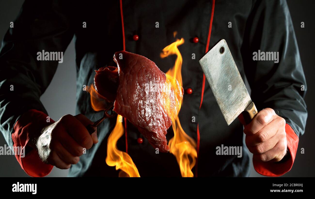 Gros plan du chef tenant le cale et le steak de bœuf cru au feu, prêt à préparer la cuisson. Banque D'Images