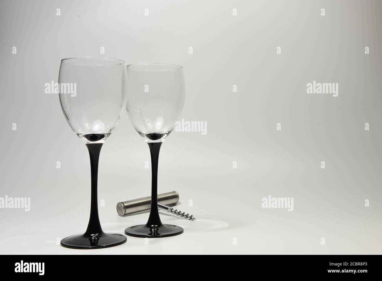 Deux verres à vin avec tiges noires et une bouteille de vin ouvreur Banque D'Images