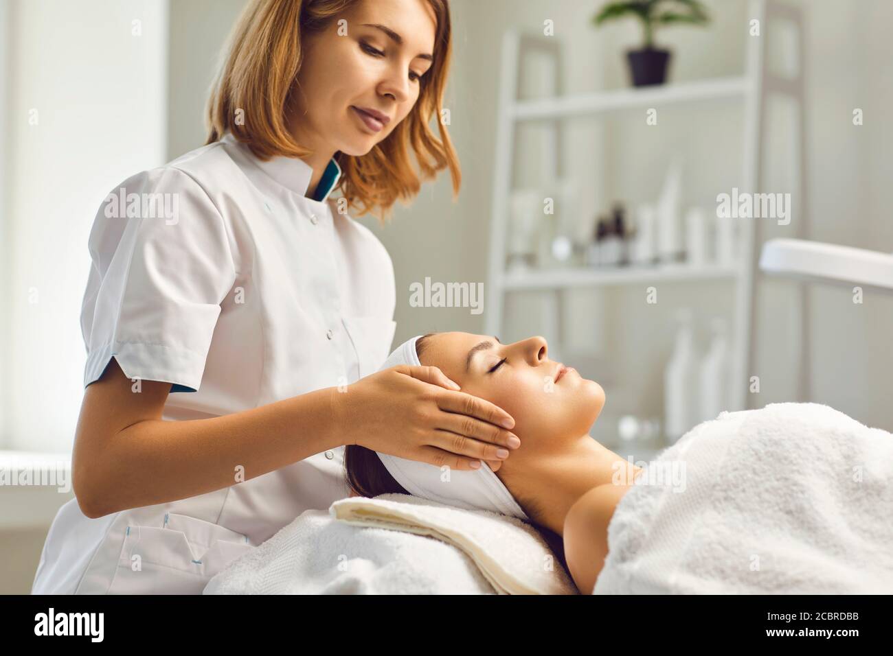 Procédures de soin de la peau du visage. Une esthéticienne fait un massage avec le visage d'une femme dans une clinique cosmétique Banque D'Images