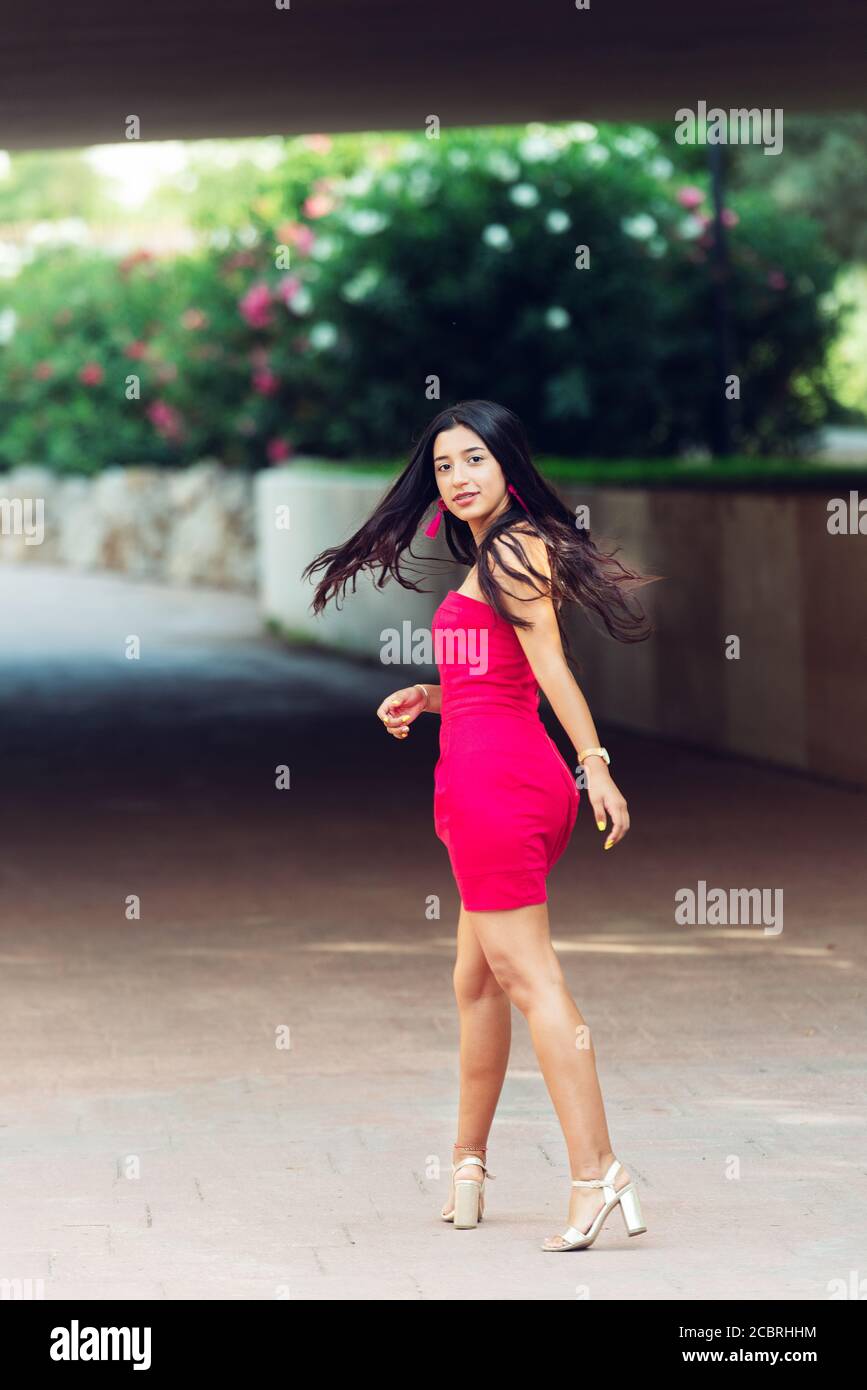 Jeune brunette Latina à cheveux longs, debout dans une longue robe donnant un voile sur elle-même avec les cheveux soufflant dans le vent. Mode concept Banque D'Images