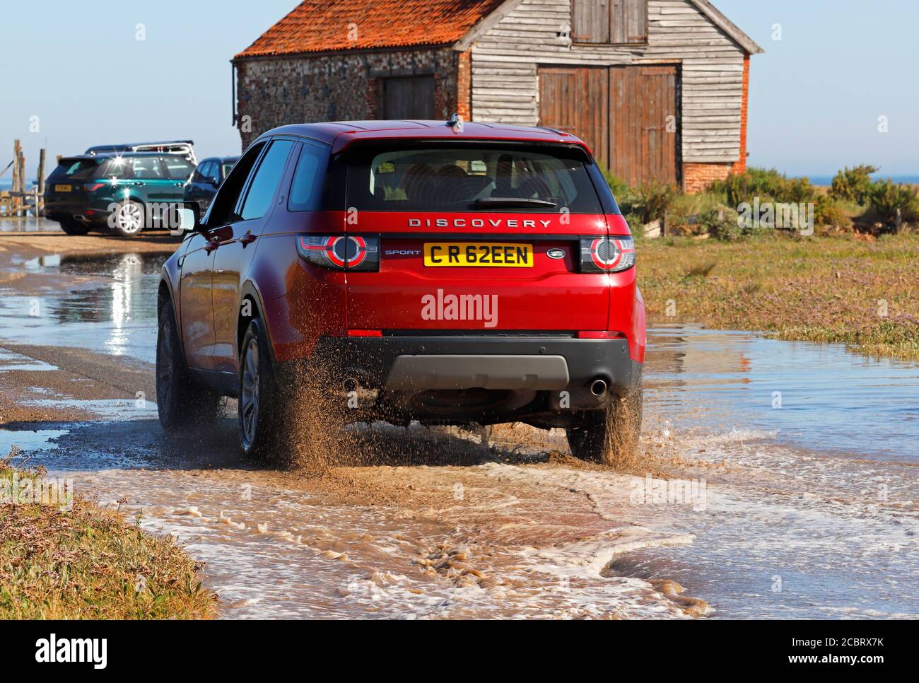 Un Land Rover Discovery traversant les eaux d'inondation marémotrice par la Barn de charbon et le port de North Norfolk à Thornham, Norfolk, Angleterre, Royaume-Uni. Banque D'Images