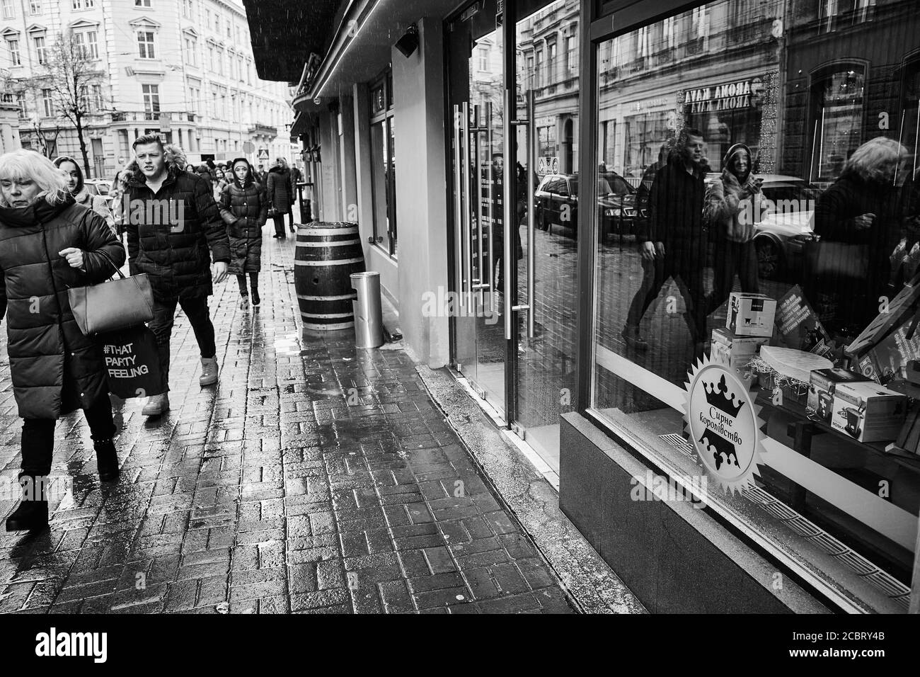 Lviv/Ukraine - 30 janvier 2020 : lors d'un jour pluvieux d'hiver, les habitants de la rue Akademika Hnatyuka marchent le long du trottoir, reflété dans la vitrine Banque D'Images