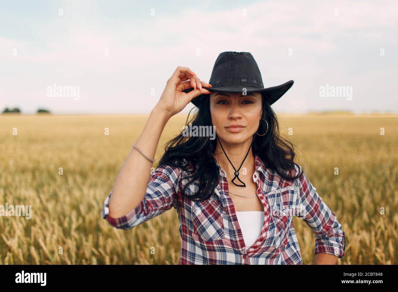 Femme paysanne américaine portant un chapeau de cowboy, une chemise à  carreaux et un Jean au champ de blé Photo Stock - Alamy