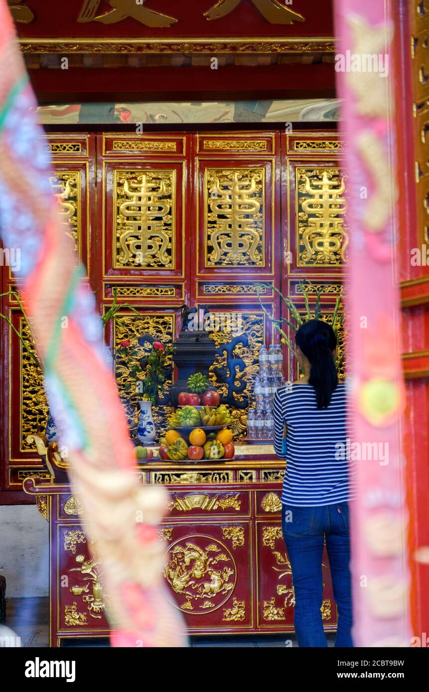 Hanoï, Vietnam. Femme priant dans un temple. Prise de vue à plage dynamique élevée. Banque D'Images