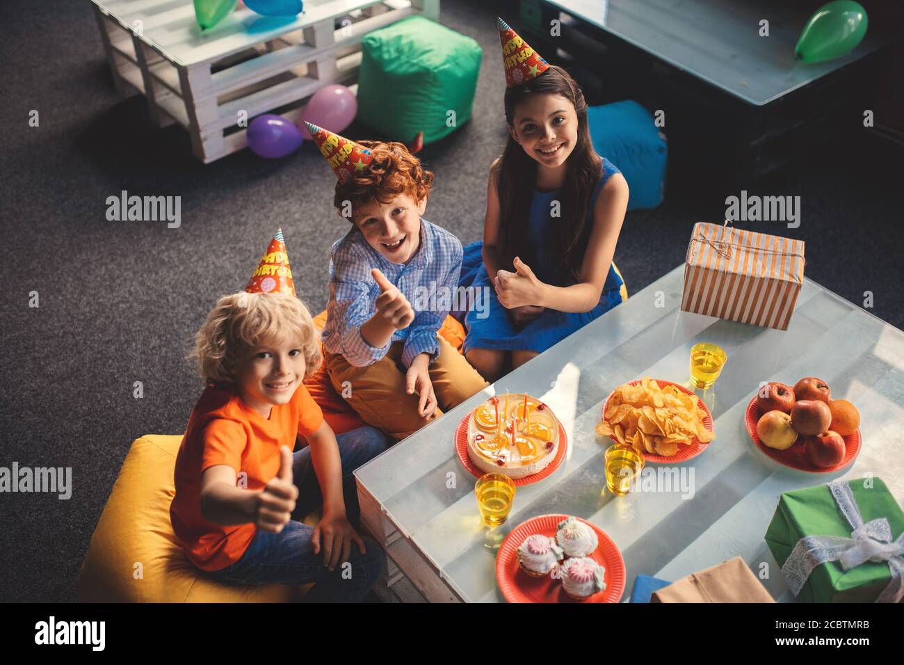 Trois enfants assis à la table et célébrant le jour de la fête Banque D'Images