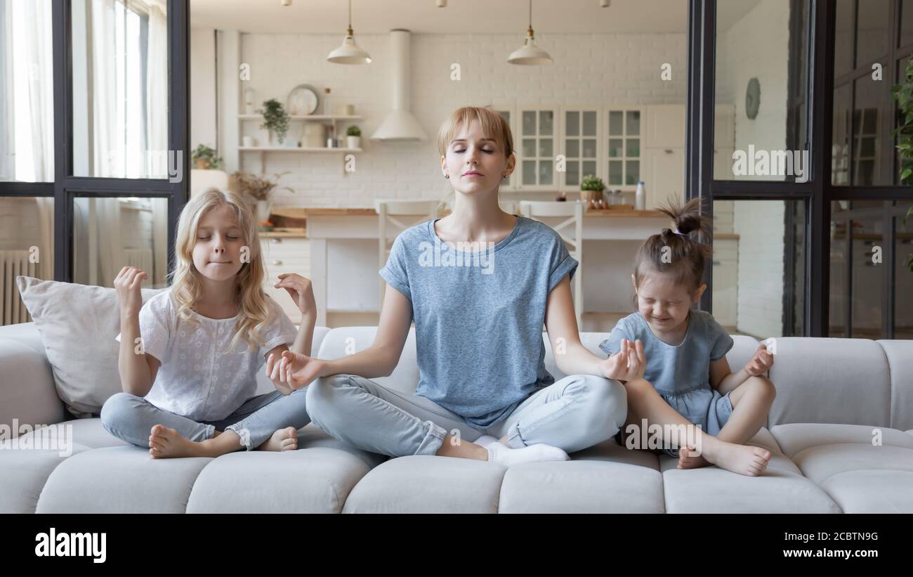 Mère et deux petites filles pratiquant le yoga à la maison Banque D'Images
