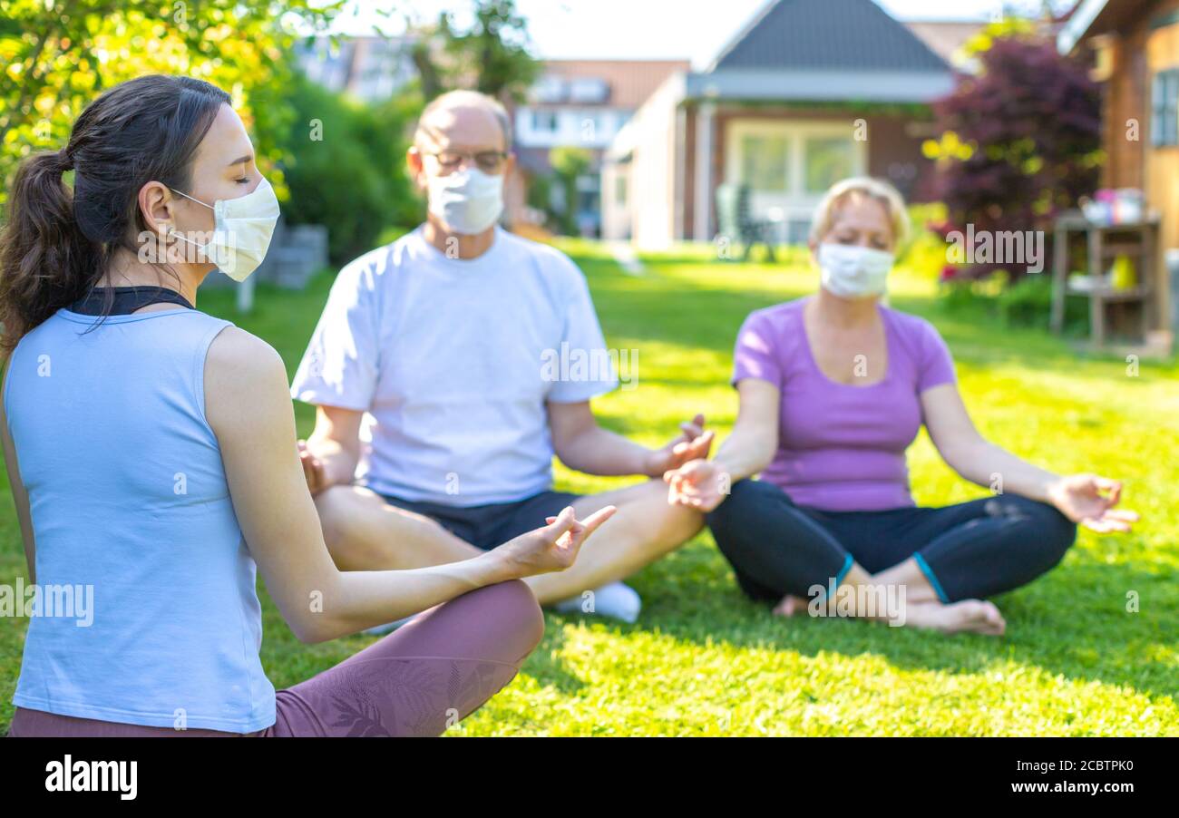 Session de groupe de yoga avec masques de visage - leçon de méditation dans une maison de soins pendant ou après le virus corona (covid-19) épidémie Banque D'Images