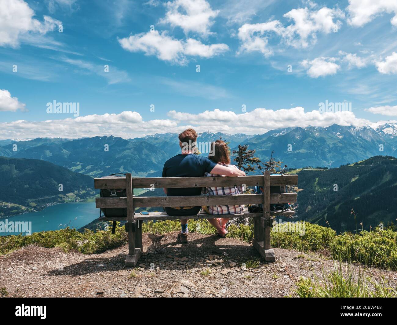 Jeune couple assis sur un banc au sommet d'une montagne Profitez du panorama de Zell am Zee en Autriche Banque D'Images
