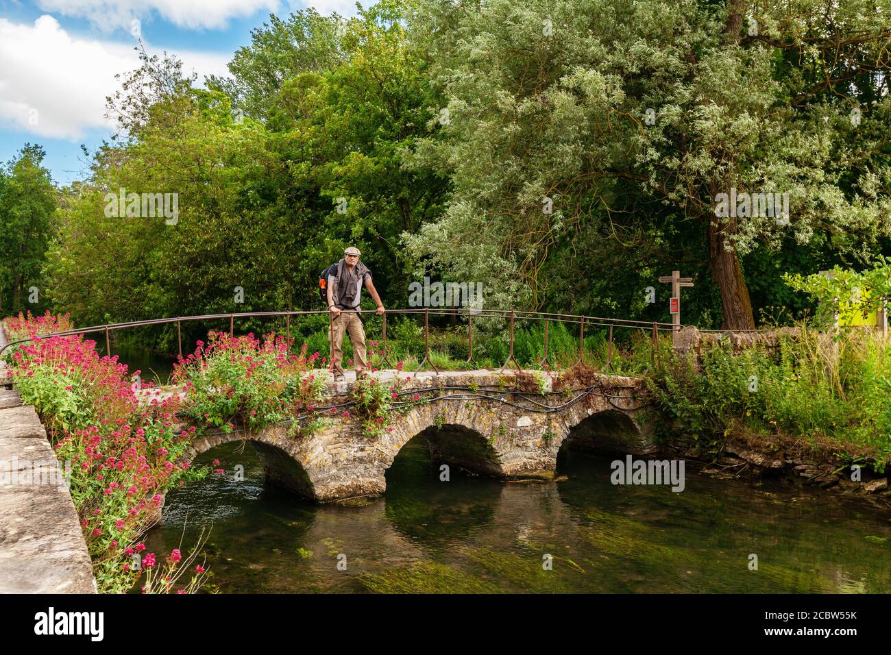 Cycliste sur le pont Old Stone sur la rivière Colne à Bilbury, Cotswold, Angleterre Banque D'Images