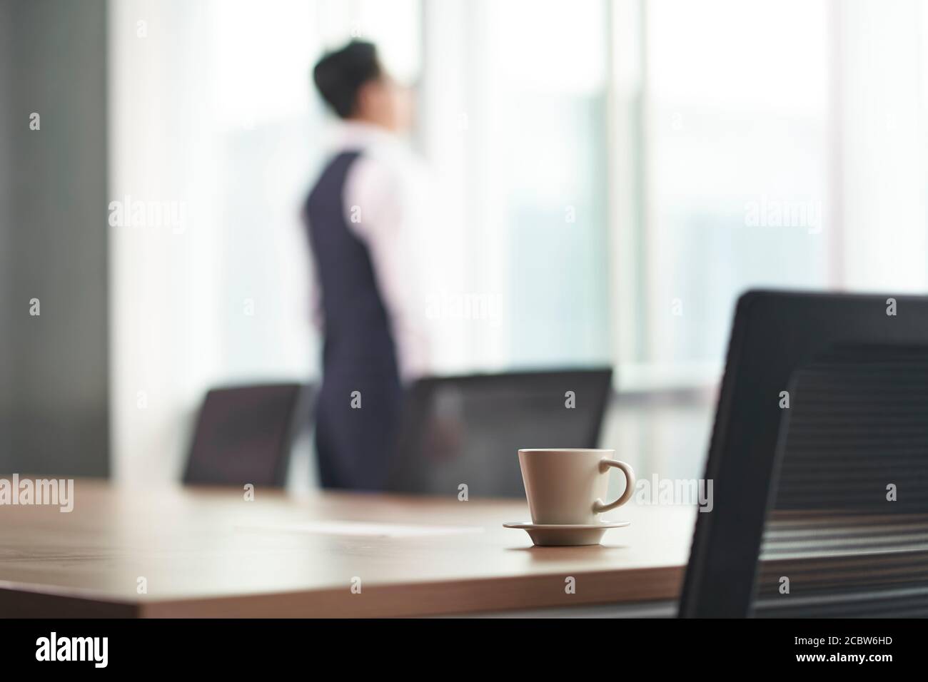 homme d'affaires asiatique debout devant la fenêtre dans la pensée de bureau, les mains dans les poches, se concentrer sur le premier plan Banque D'Images