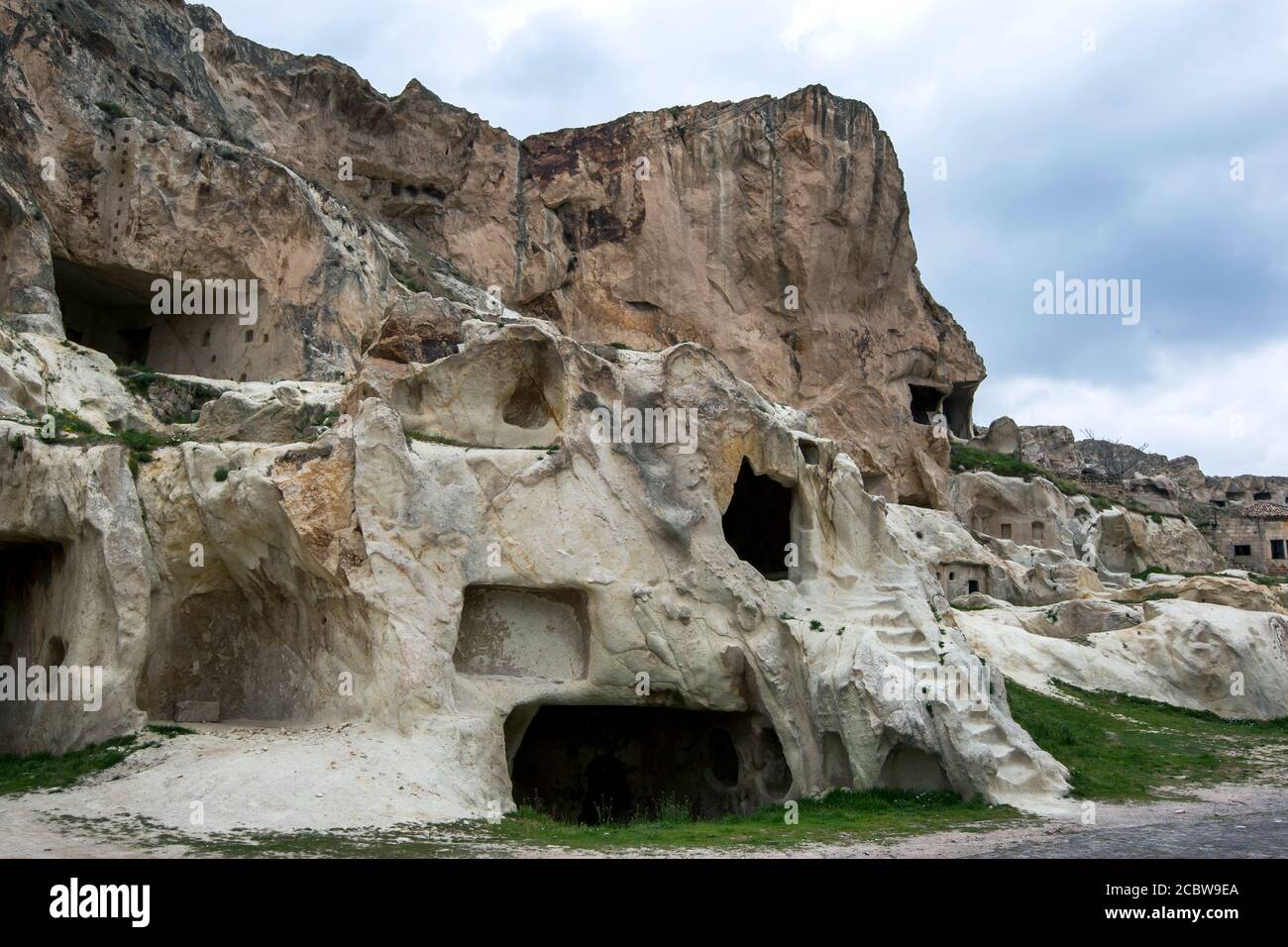 Les ruines des anciennes maisons de grottes et des escaliers sculptés dans une falaise de roche face près d'Urgup dans la région de Cappadoce en Turquie. Banque D'Images