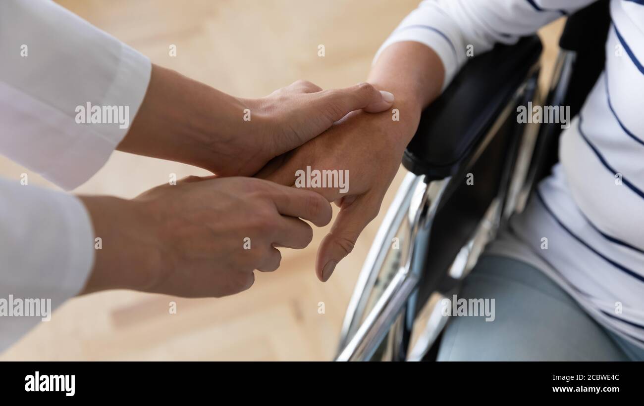 Travailleur social médical tenant la main d'un vieux patient handicapé. Banque D'Images