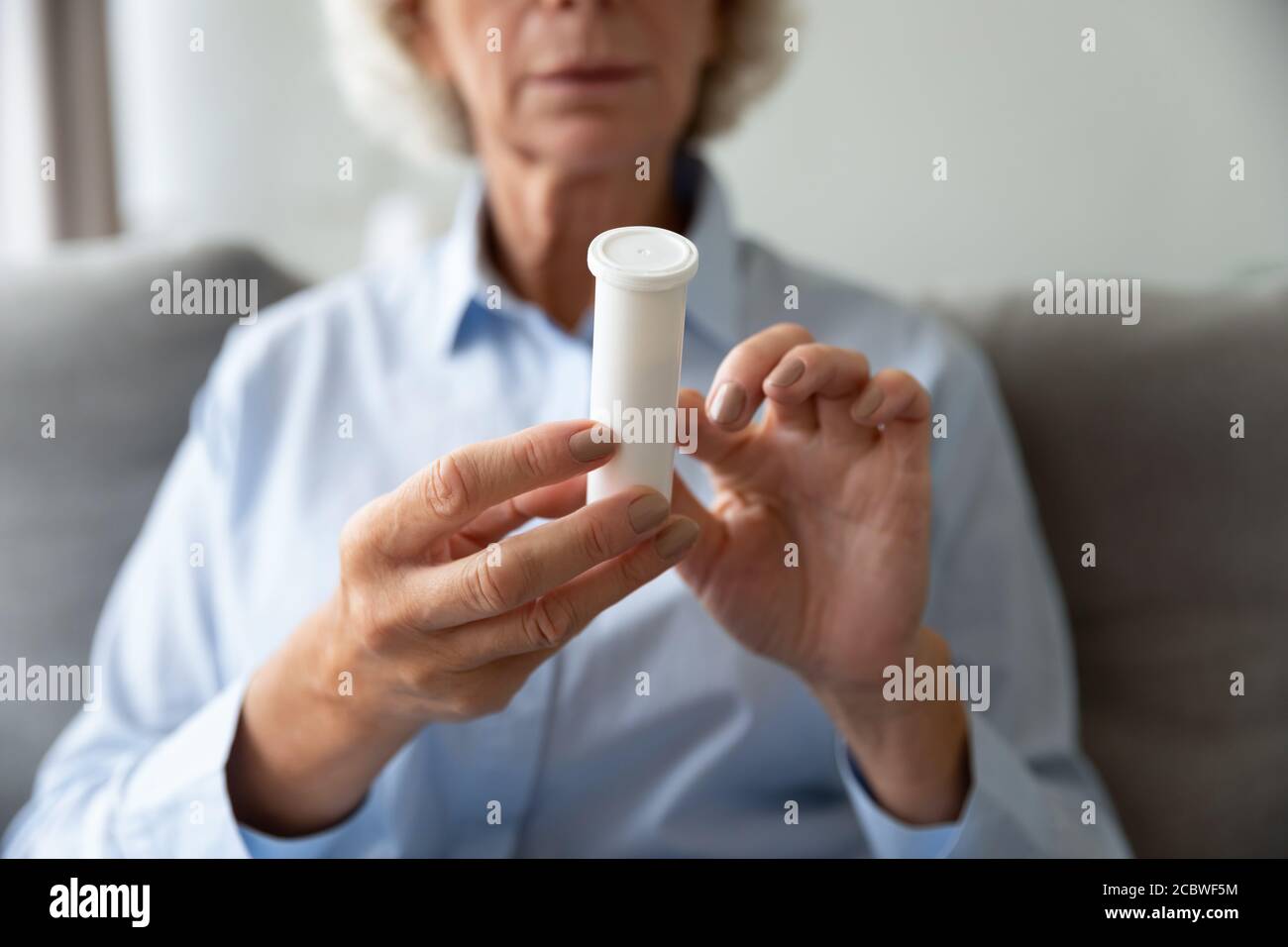 Fermez le flacon en plastique avec des pilules dans les mains froissées de la femme Banque D'Images