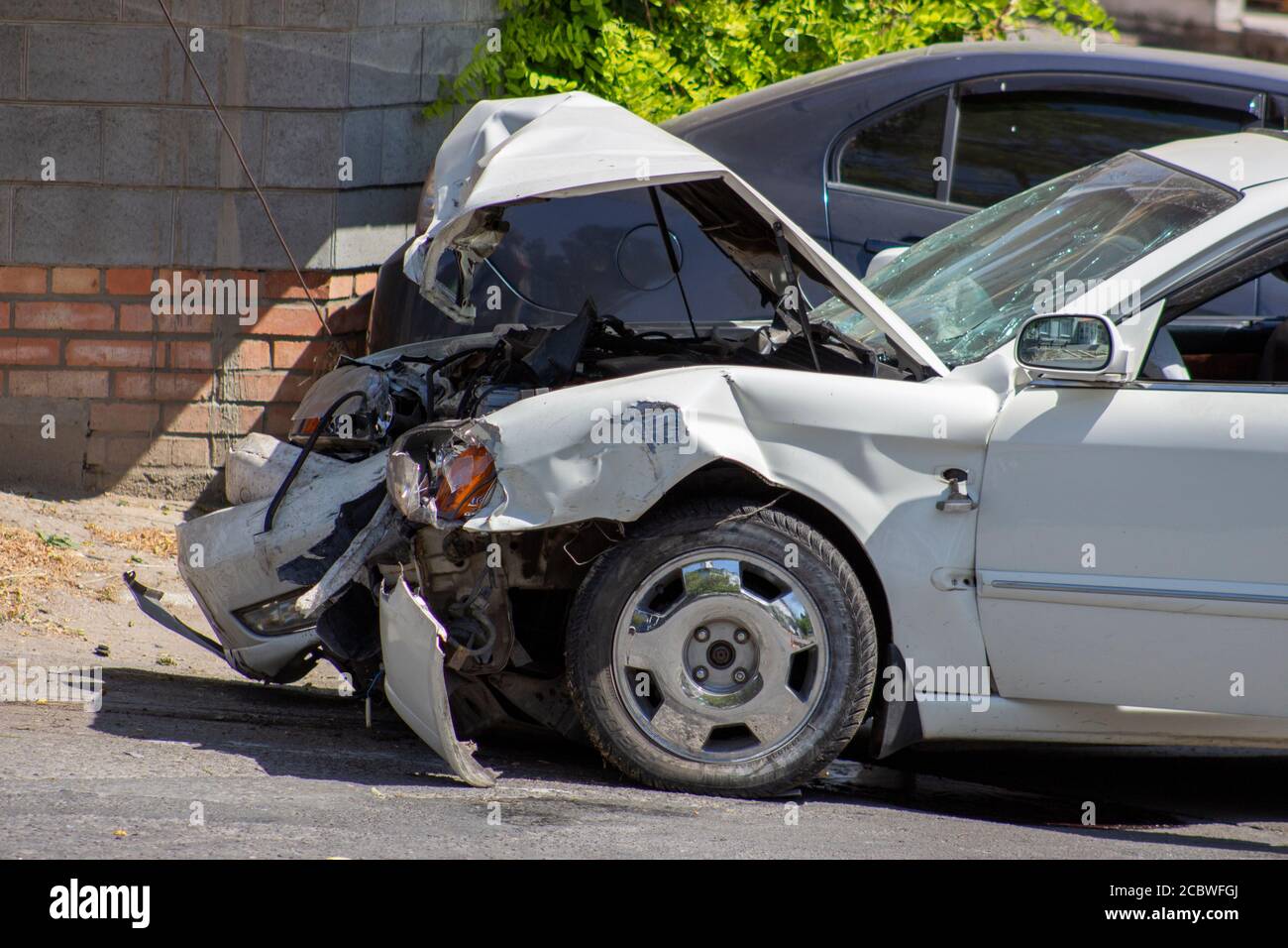 Un accident de la route, une voiture qui s'est écrasée, une voiture blanche sur la route, des fissures dans le verre et un pare-chocs endommagé. Banque D'Images