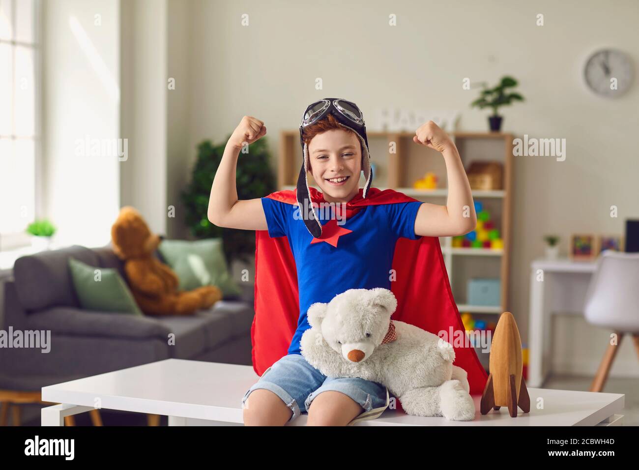 Joyeux garçon en costume de super-héros montrant la force à la maison.  Enfant créatif habillé comme un super-homme jouant à l'intérieur Photo  Stock - Alamy