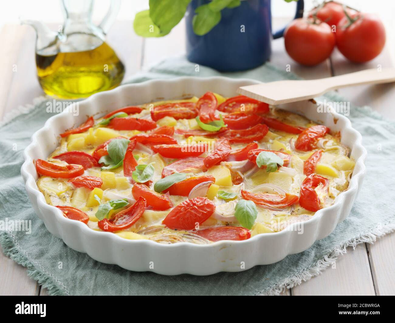 Frittata au four avec pommes de terre, oignons et tomates décorées de feuilles de basilic vert Banque D'Images