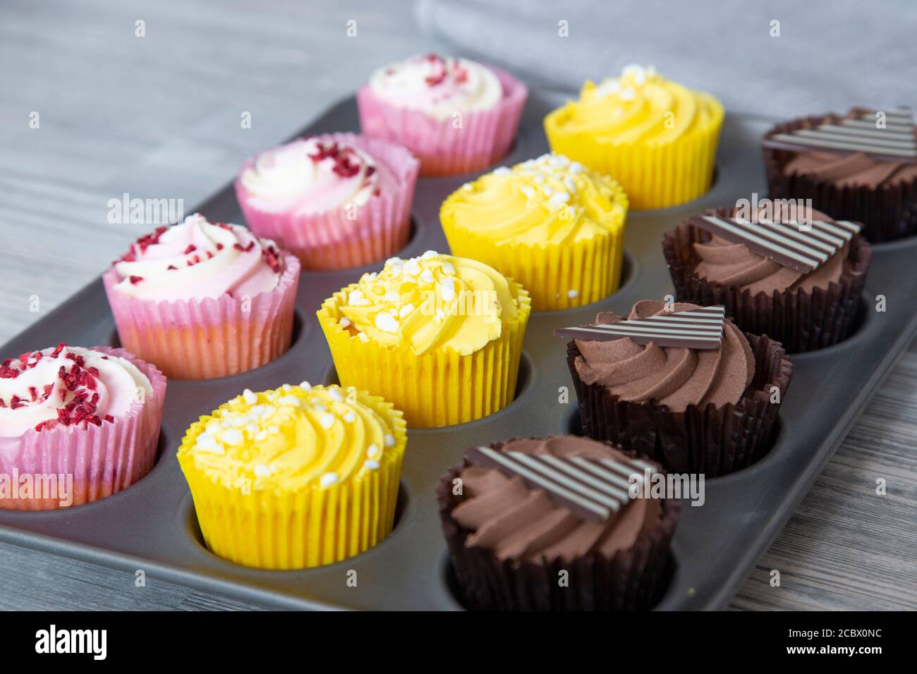 Variété de cupcakes dans une plaque de cuisson en métal fond de bois gris Banque D'Images
