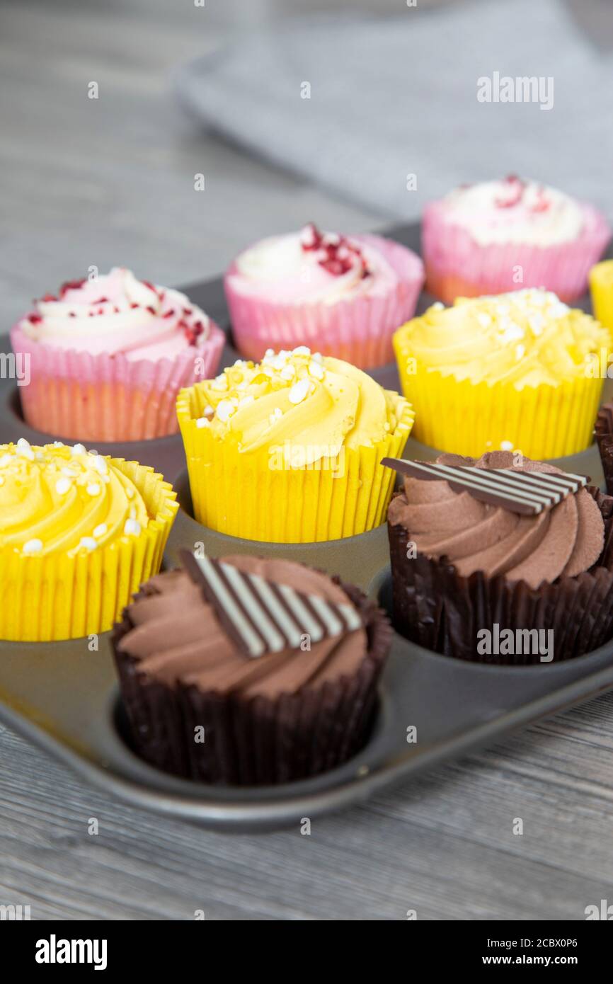 Variété de cupcakes dans une plaque de cuisson en métal fond de bois gris Banque D'Images
