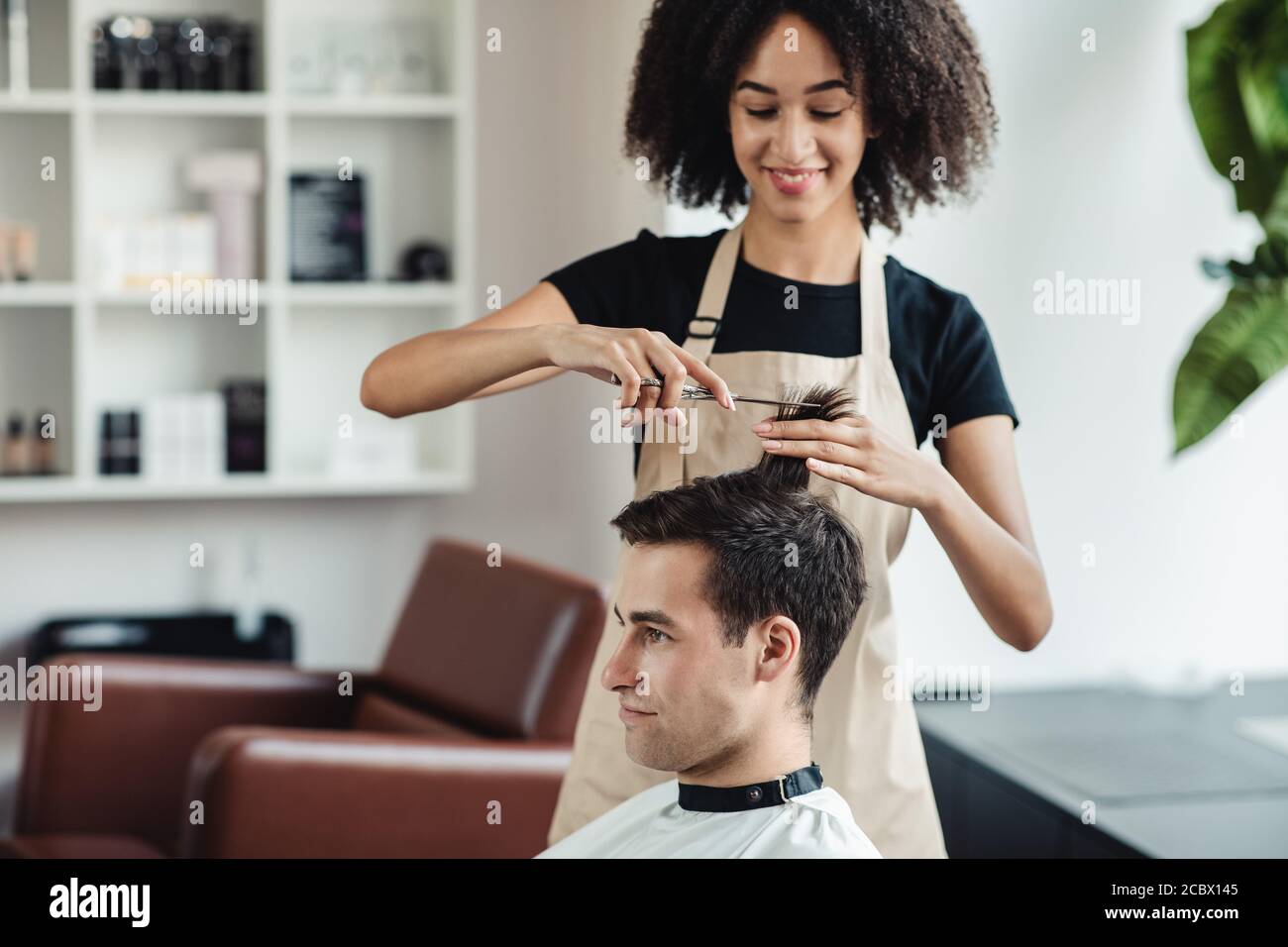 Jeune homme se couper les cheveux au salon de coiffure Banque D'Images